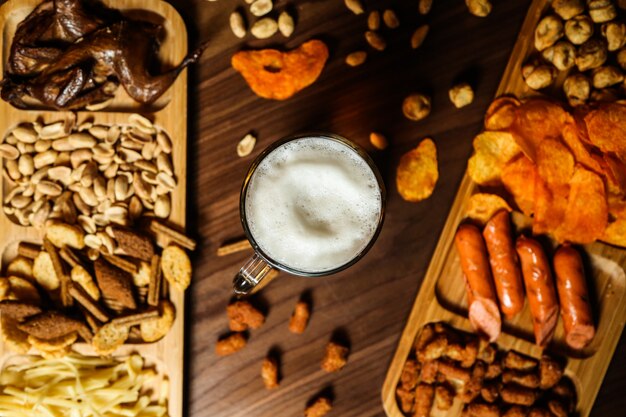 A glass of beer and various snacks on the table for it