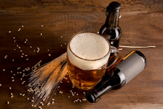 Glass of beer with brown bottles of beer on wooden table