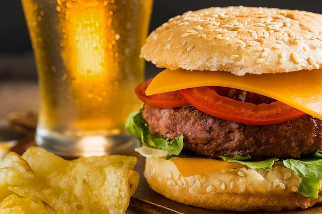 Glass of beer with cheeseburger and chips