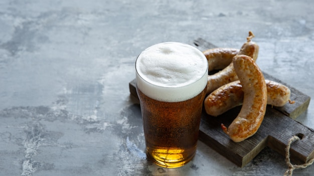 Free photo glass of beer with foam on top on white stone wall.