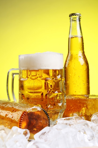 Glass of beer with foam on yellow background