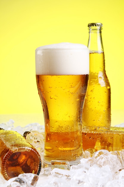 Glass of beer with foam on yellow background