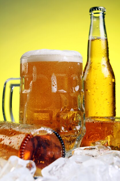 Glass of beer with foam on yellow background