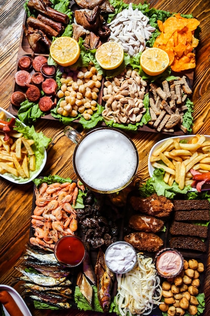 Free Photo a glass of beer with various snacks for it on the table