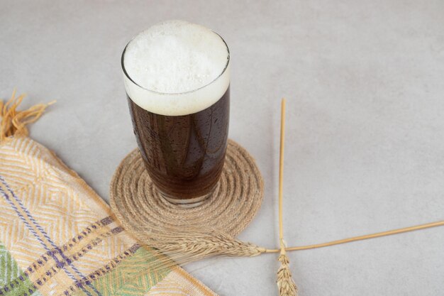 Glass of beer with wheat on stone surface