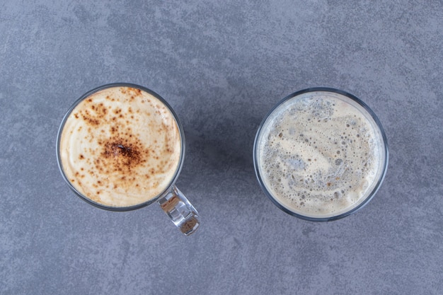 Free photo a glass of blue coffee next to chocolate cappuccino, on the blue table.