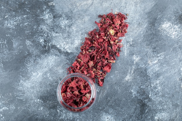 Free photo glass bottle of dried flower petals on marble table.