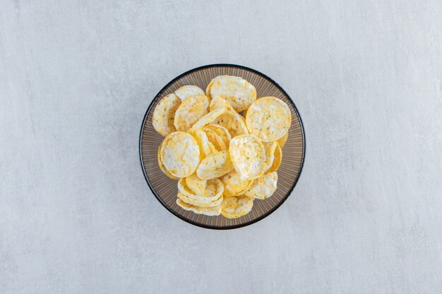 Glass bowl of crispy rice cakes on stone.