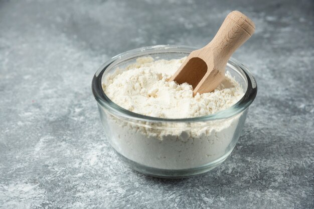 Glass bowl of flour on marble.