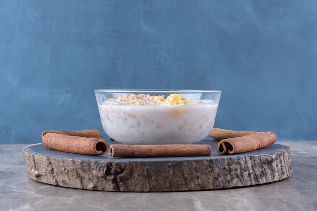 Free photo a glass bowl of healthy cornflakes with milk and cinnamon sticks