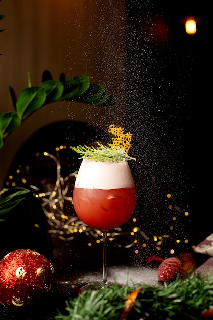 A glass of citrus cocktail garnished with pine leaves in christmas eve