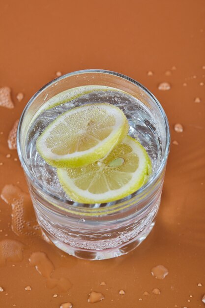 A glass of cold refreshing lemonade on orange surface