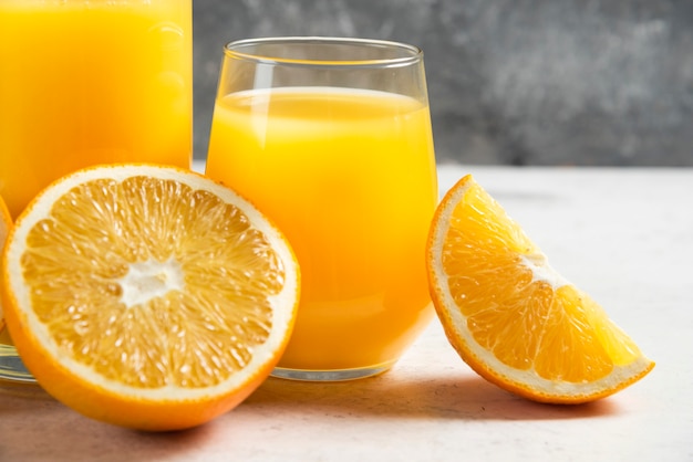 A glass cup of fresh juice with sliced orange.