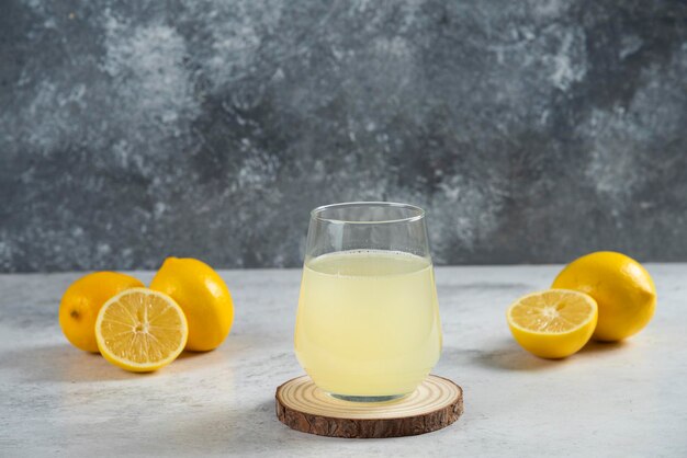 A glass cup of fresh lemon juice on a wooden board.