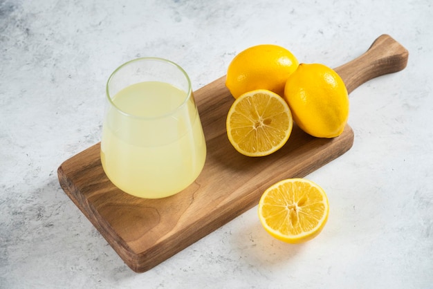 Free Photo a glass cup of fresh lemon juice on a wooden board.