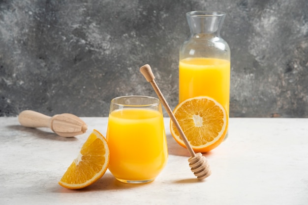 A glass cup of fresh orange juice with a wooden dipper.