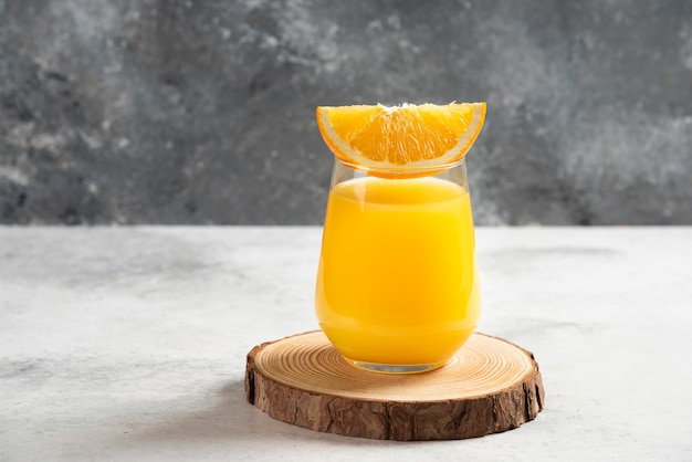 Free photo a glass cup of fresh orange juice on wooden board.