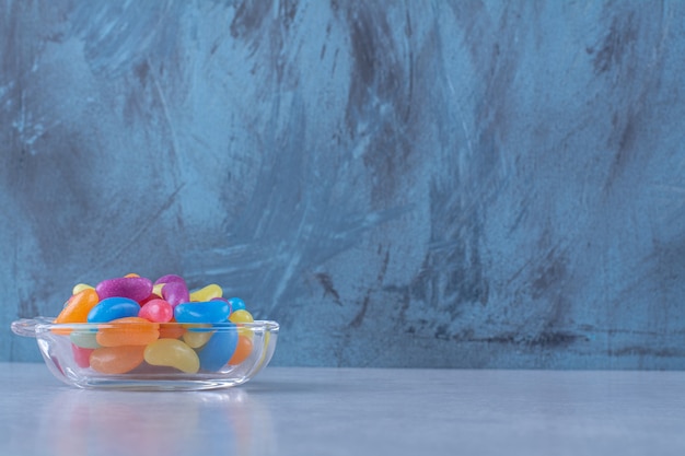 Free photo a glass cup full of colorful bean candies on gray surface.high quality photo