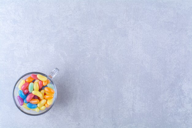 A glass cup full of colorful bean candies 