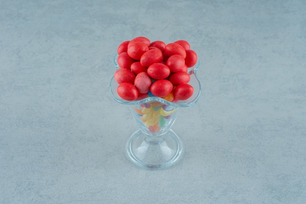 A glass cup full of colorful beans candies on a white background. High quality photo