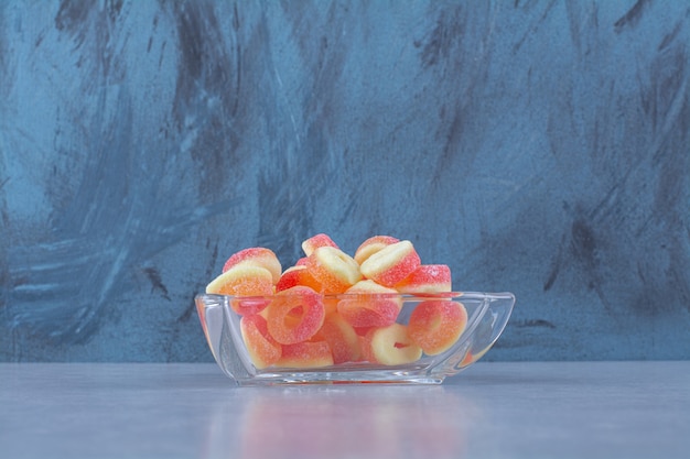 A glass cup full of colorful fruit jelly candies . 