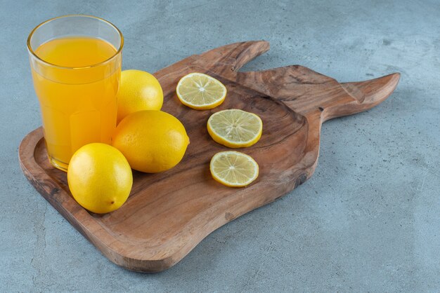 A glass cup of orange juice with fresh lemons . 