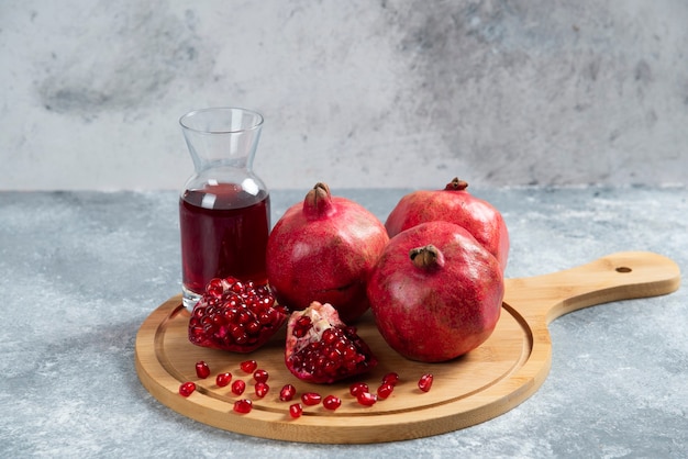 A glass cup of pomegranate juice on a wooden board.