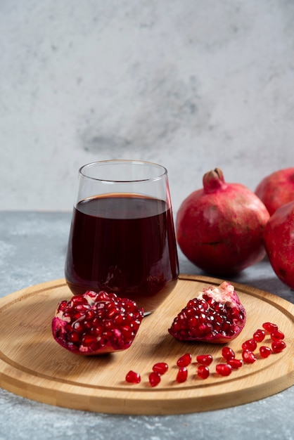 A glass cup of pomegranate juice on a wooden board.