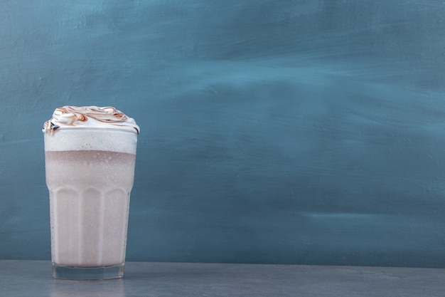 A glass cup of sweet milkshake with whipped cream . High quality photo