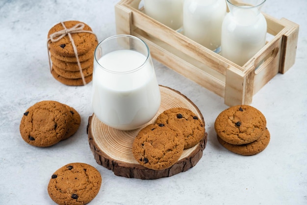 A glass cup with chocolate cookies on a wooden desk.