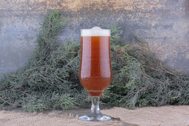 Glass of dark beer on burlap with pine branch. High quality photo