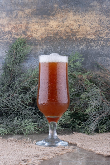 Glass of dark beer on burlap with pine branch