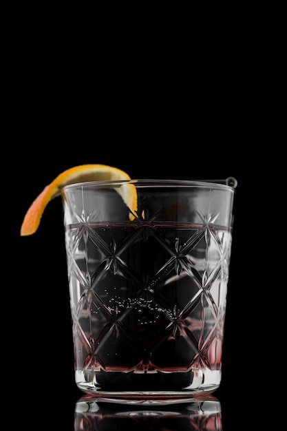 Glass of drink with orange slice and black background