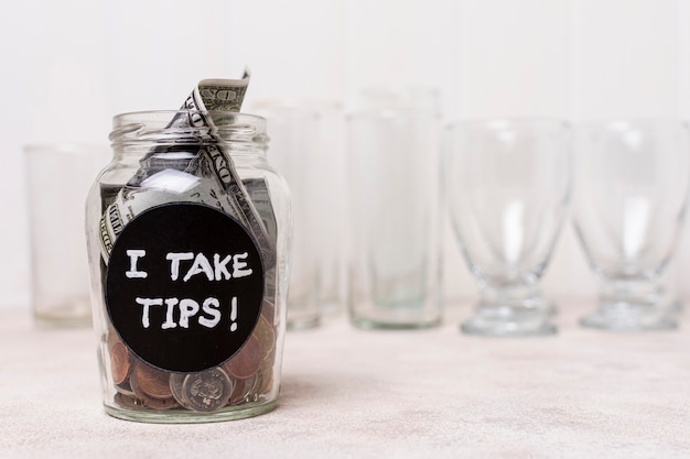 Glass filled with money and empty glasses in the background