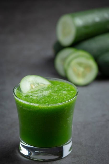 Glass of fresh cucumber juice on dark background