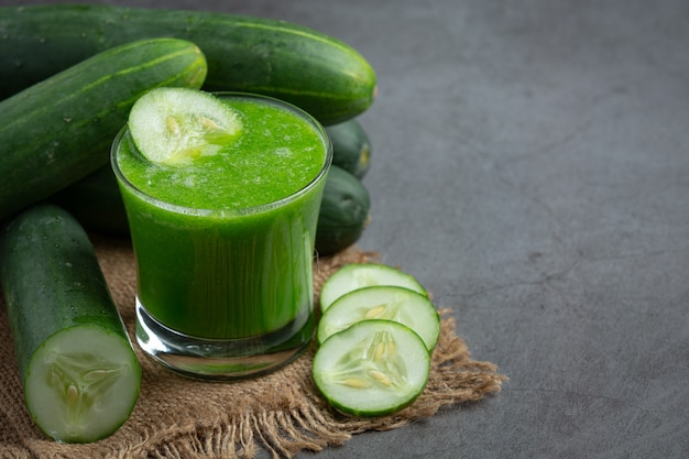 Glass of fresh cucumber juice on dark background