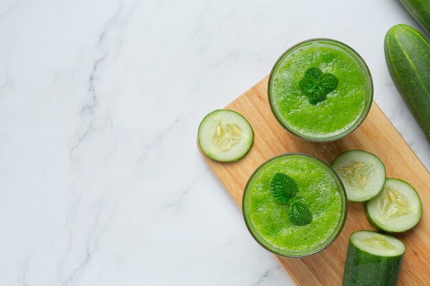 Glass of fresh cucumber juice on marble background