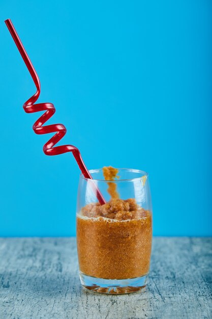 A glass of fresh smoothie with straw on gray table. 