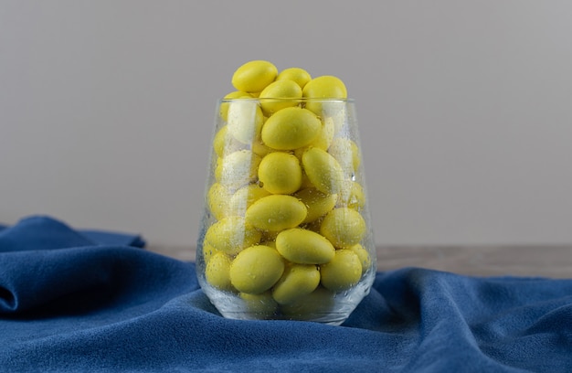 Glass full of yellow gum on the towel, on the marble surface