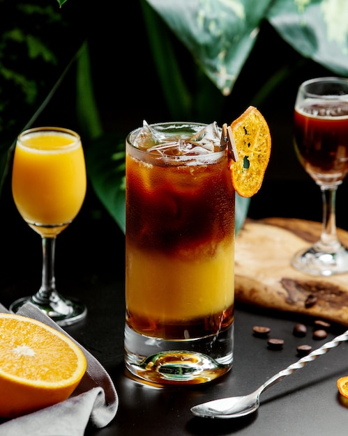 A glass of a glass of orange cocktail garnished with dried orange slice