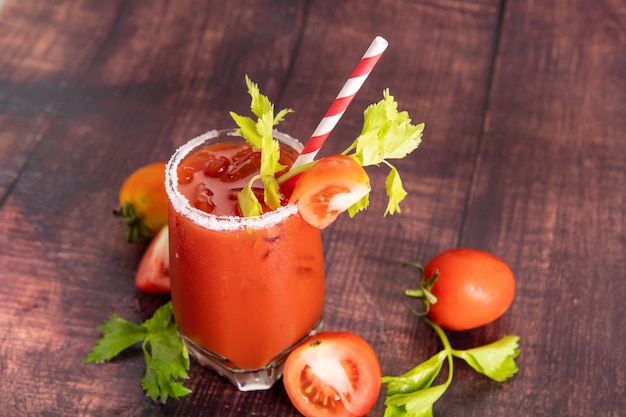 Glass glass of tomato juice with fresh bright tomatoes, green parsley  on a dark background. vegetable drink.