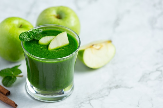 Glass of green apple healthy smoothie put next to fresh green apples