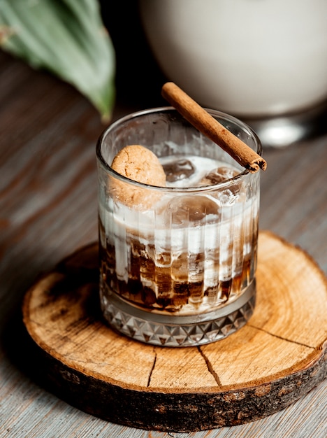 glass of iced coffee cocktail garnished with cinnamon stick