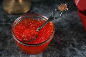 Free photo a glass jar with red caviar on a blue table