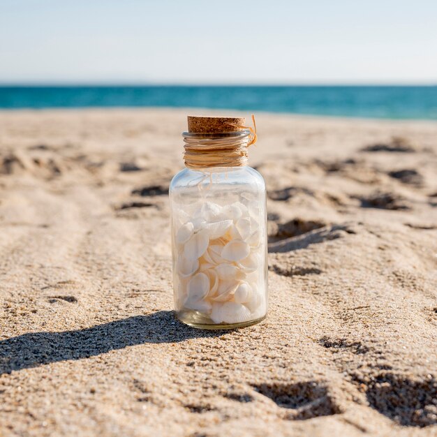 Glass jar with shells on sand