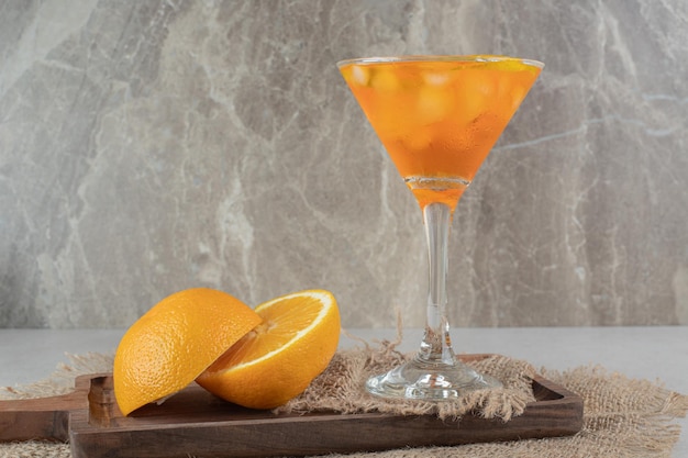 Free photo a glass of juice with citrus fruits on wooden board