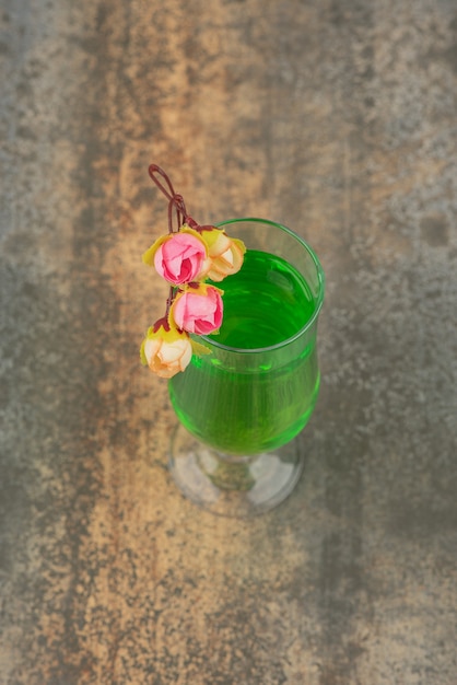 Free Photo a glass of juicy green lemonade and roses on marble wall.