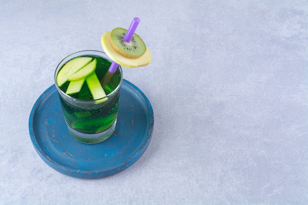 Free photo glass of kiwi juice on a wooden plate, on the marble table.