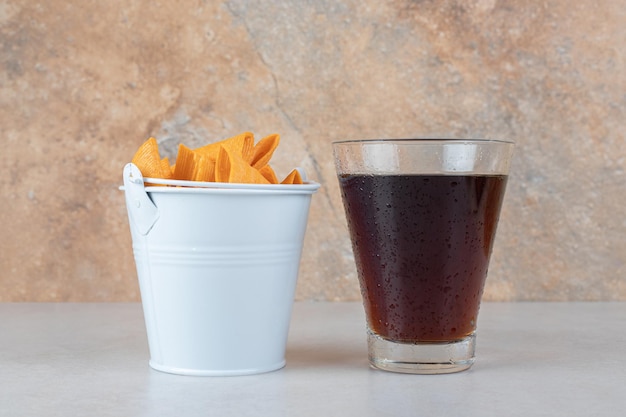 Free photo glass of lemonade and bucket of triangle shaped chips.