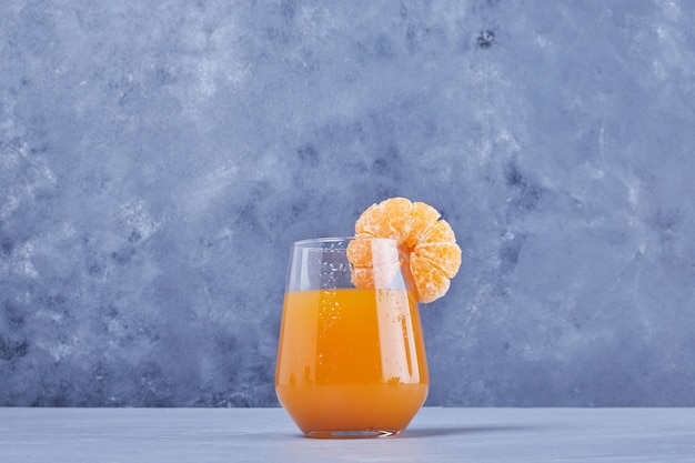 A glass of mandarin juice with fruit.